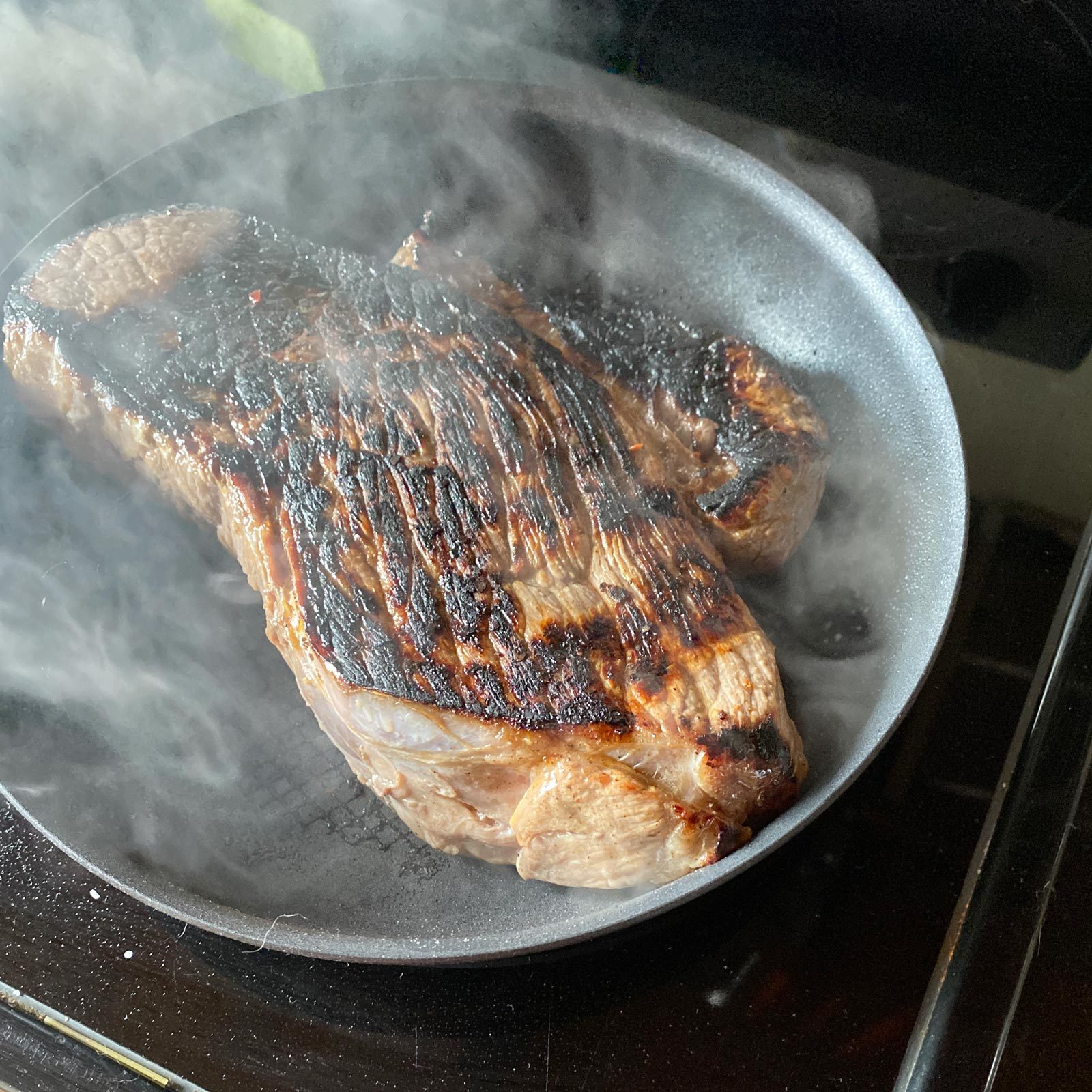 steak in a pan on the stove with cooked side up