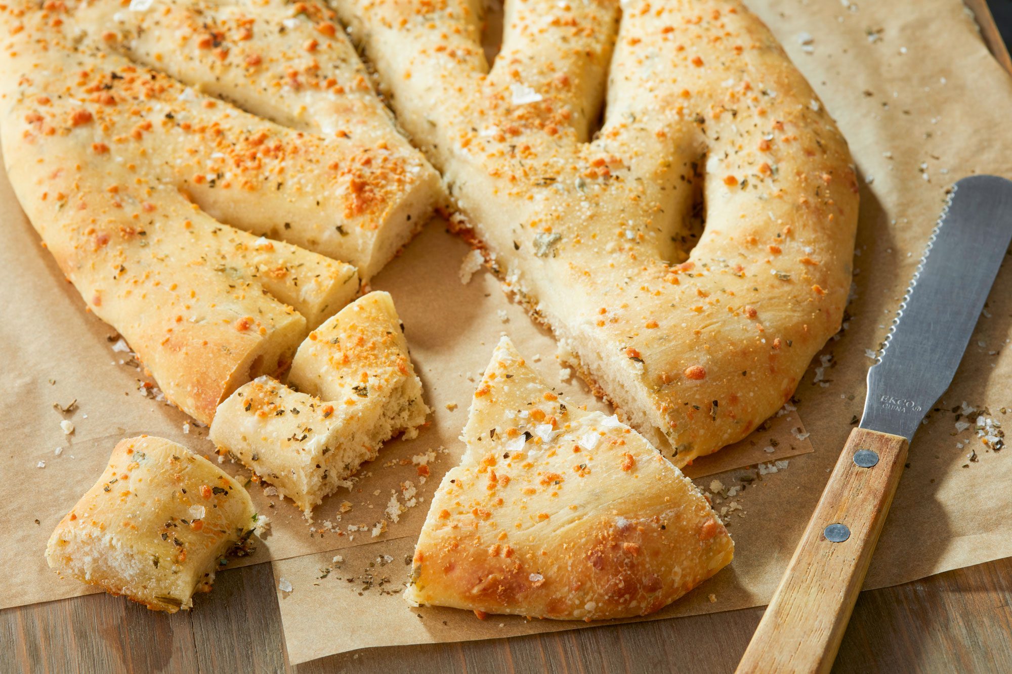 Fougasse on a Baking Paper on Wooden Serving Plate with Knife
