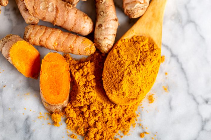 Food and drink, diet nutrition, health care concept. Raw organic orange turmeric root and powder, curcuma longa on a grunge cooking table. Indian oriental low cholesterol spices