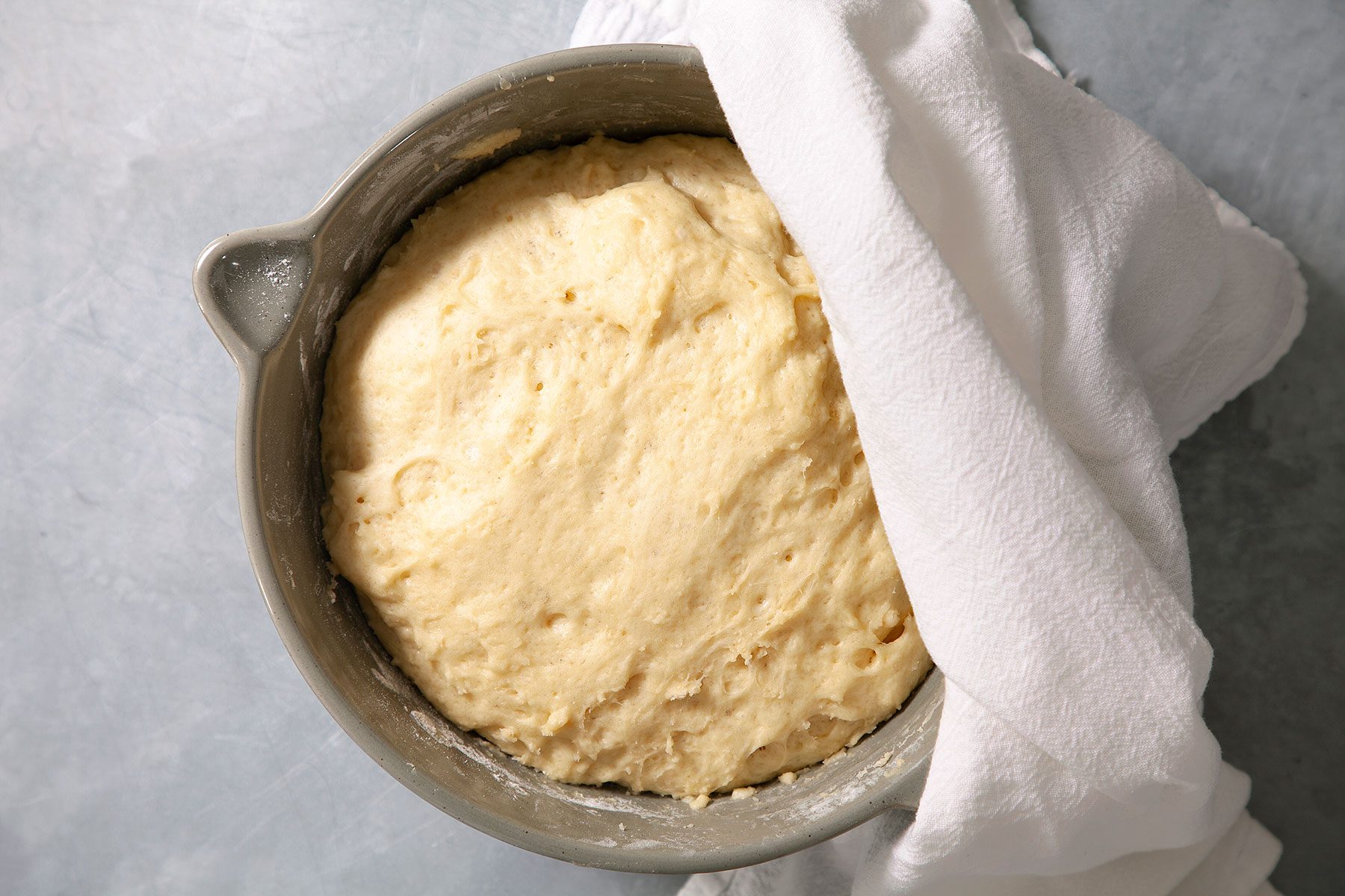Dough resting in large bowl with cloth over it