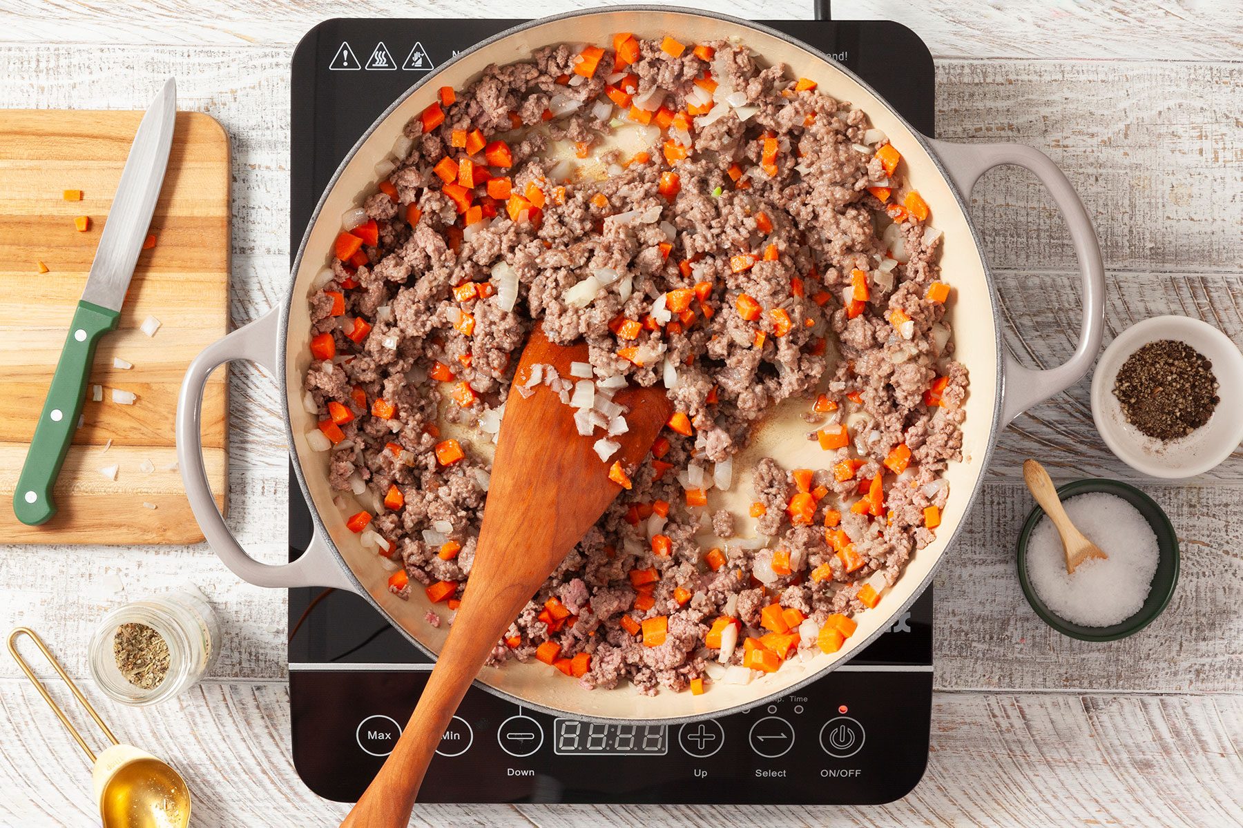 Mixing meat and vegetables in skillet