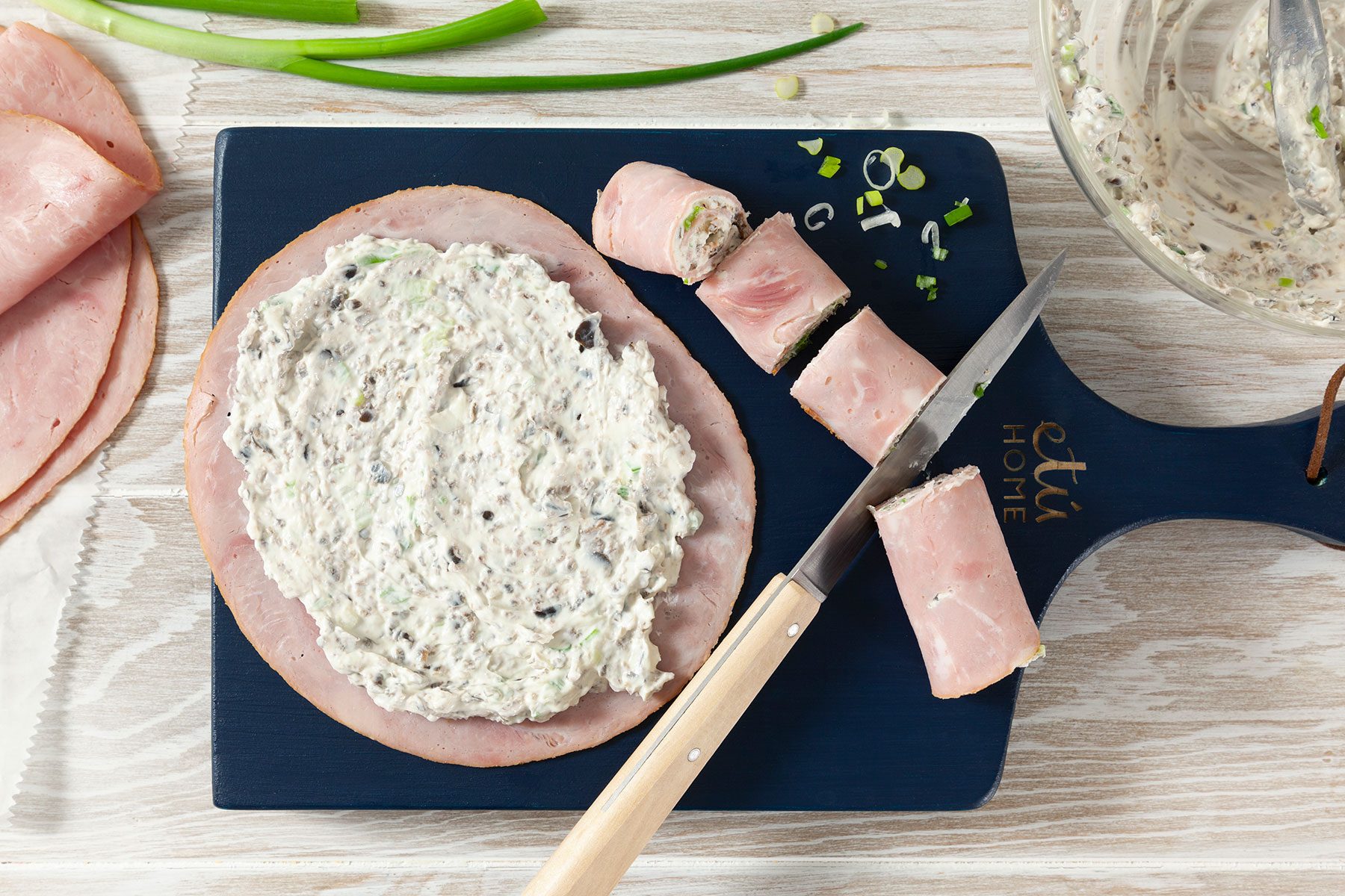 Spreading cream cheese on ham