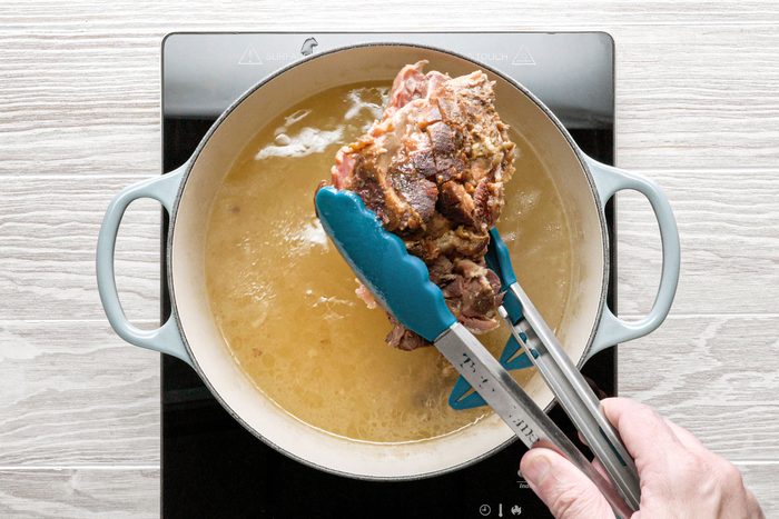 Removing the half cooked ham bone from a large dutch oven