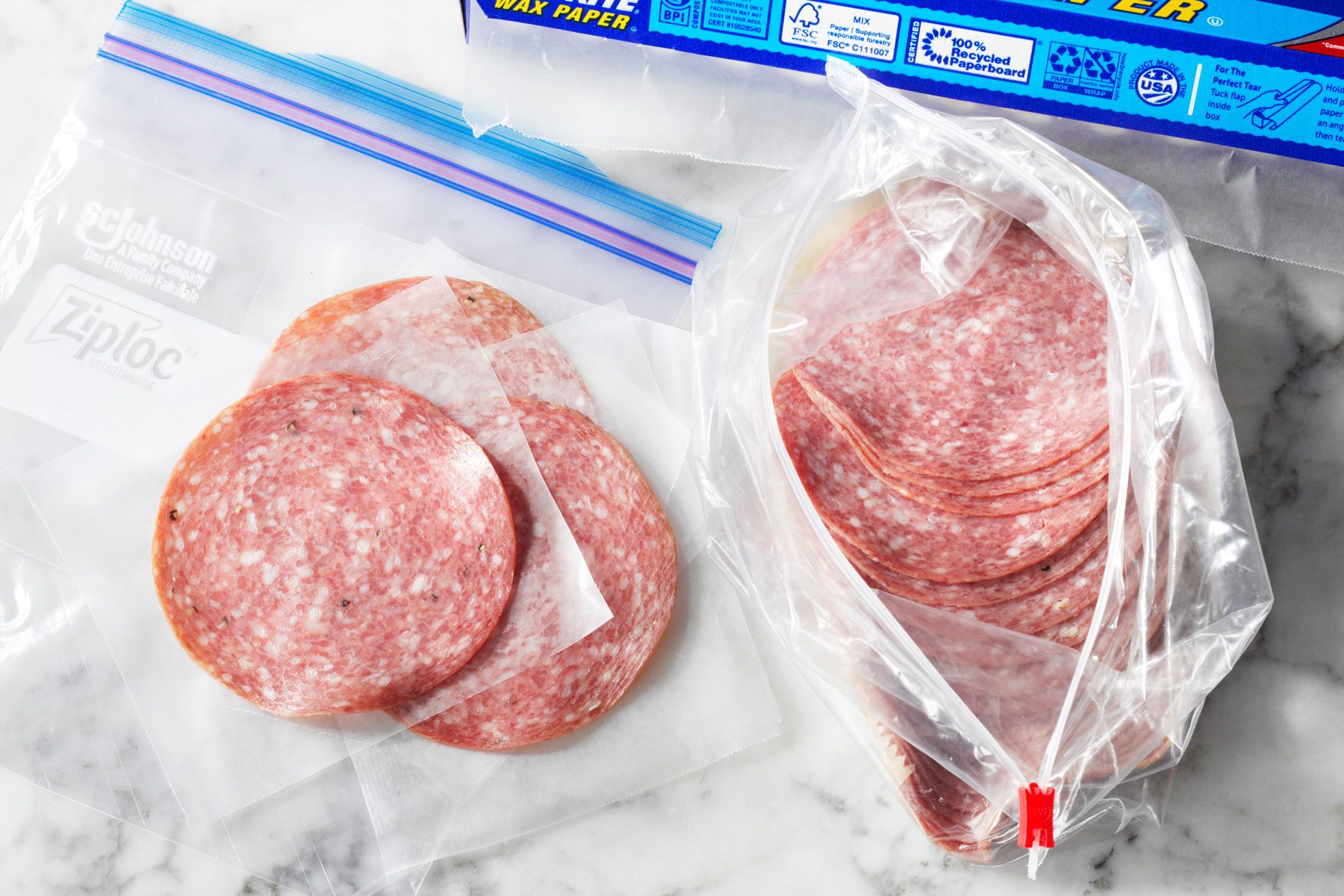 Fresh deli meat being packaged for proper freezing with a piece of wax paper between each slice