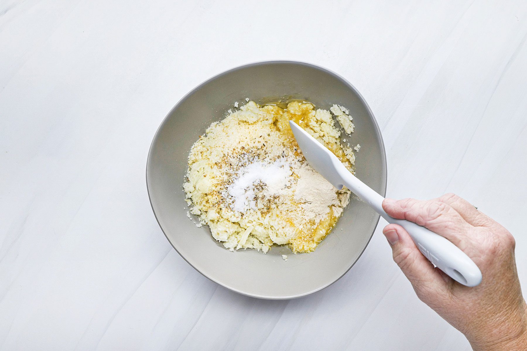Mixing the cauliflower crust with cheese in a small bowl