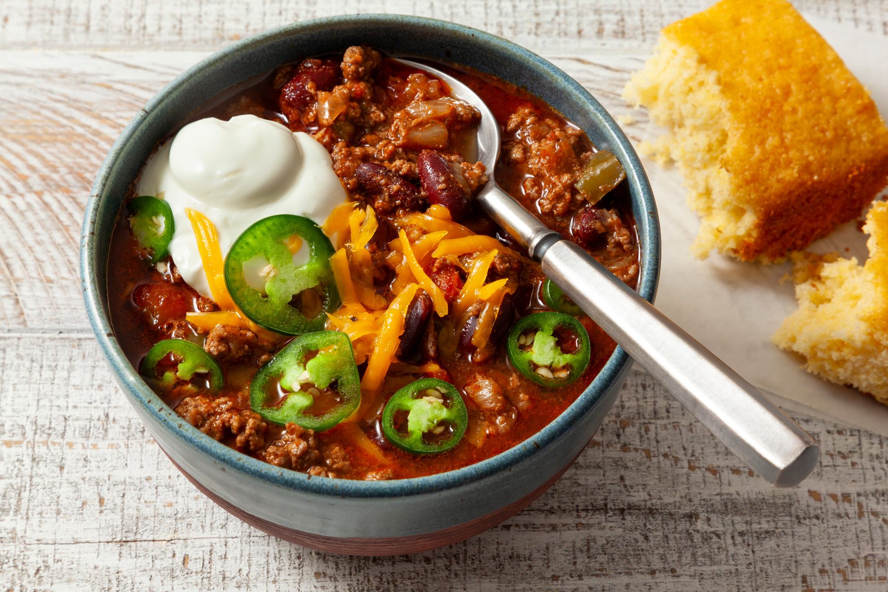 A bowl of chili con carne garnished with sour cream and jalapeno