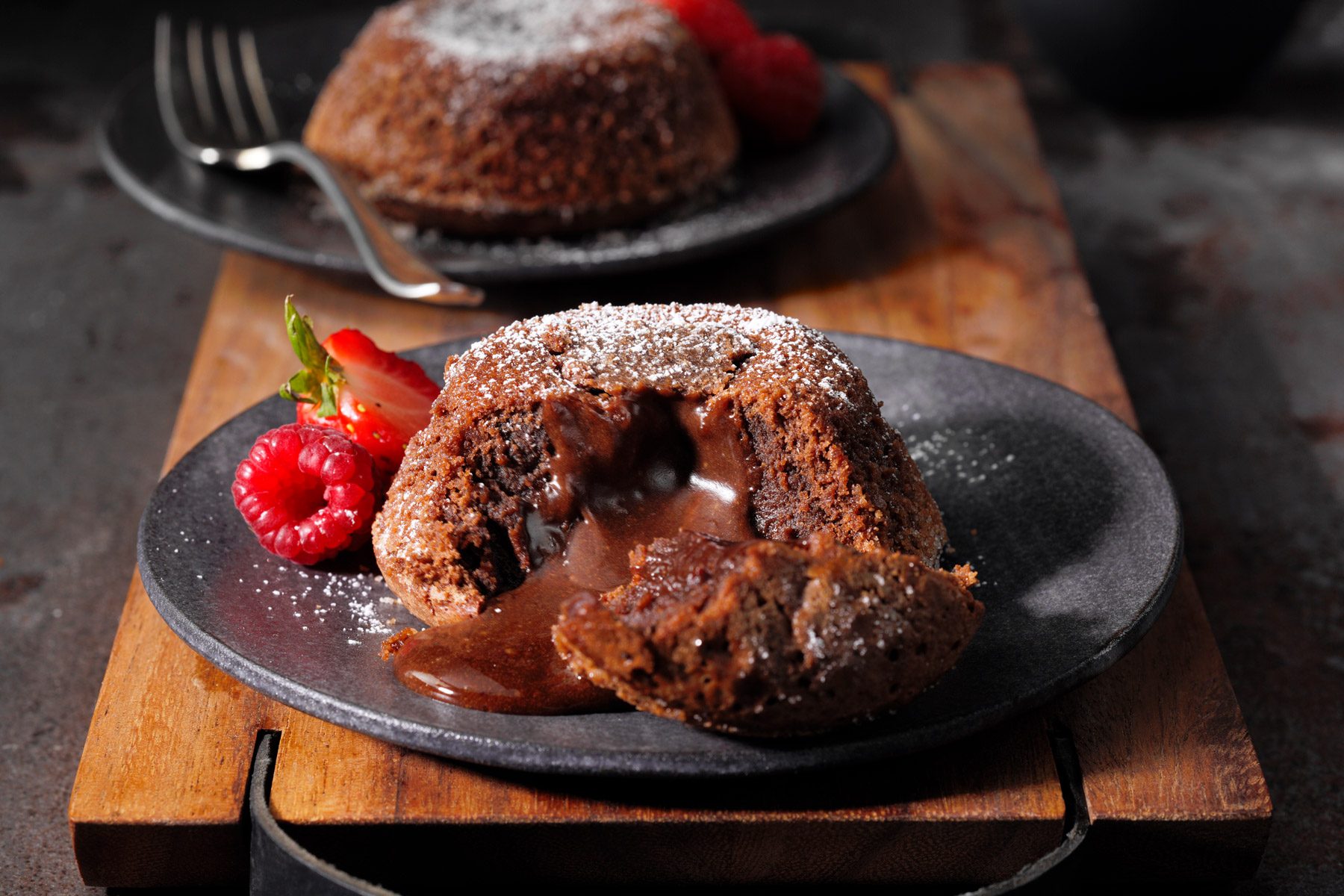 A chocolate lava cake with a chocolate sauce and strawberries