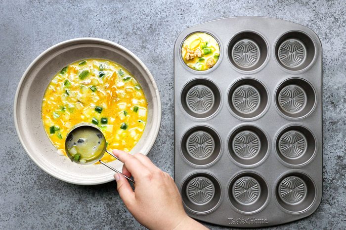 Spooning the batter into muffin cups from a large bowl