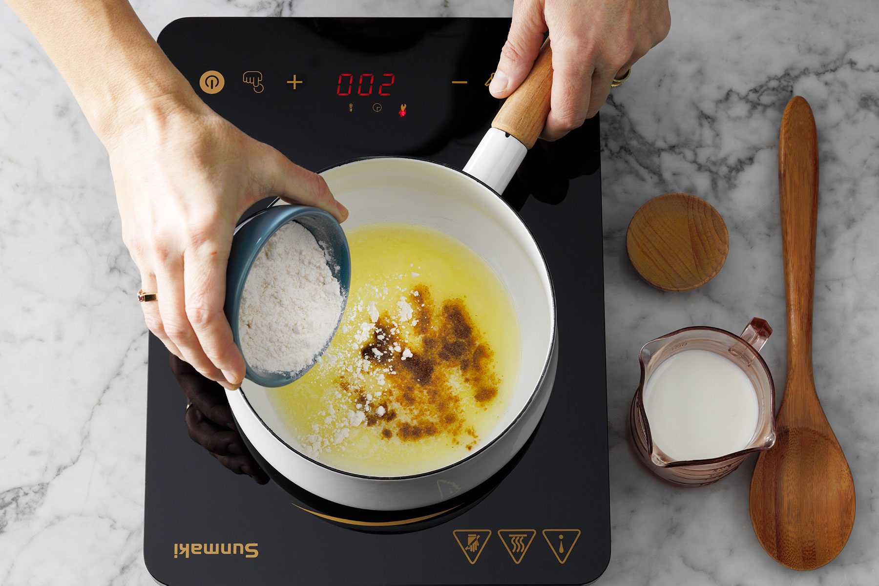 Adding flour and curry powder in melted butter in saucepan 