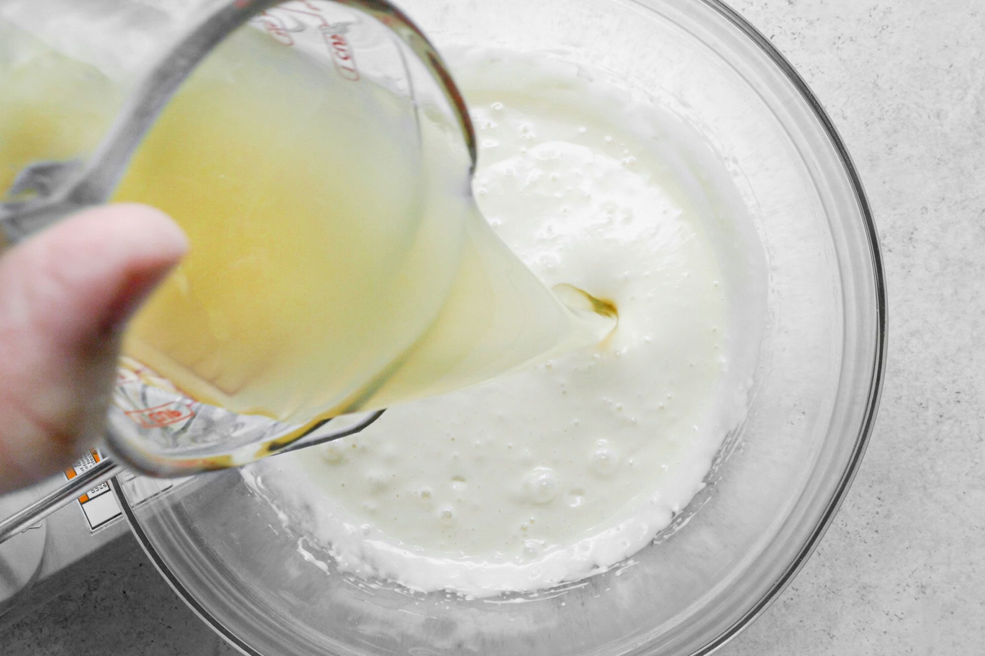 pouring lemonade concentrate into pie mixture in a large glass bowl