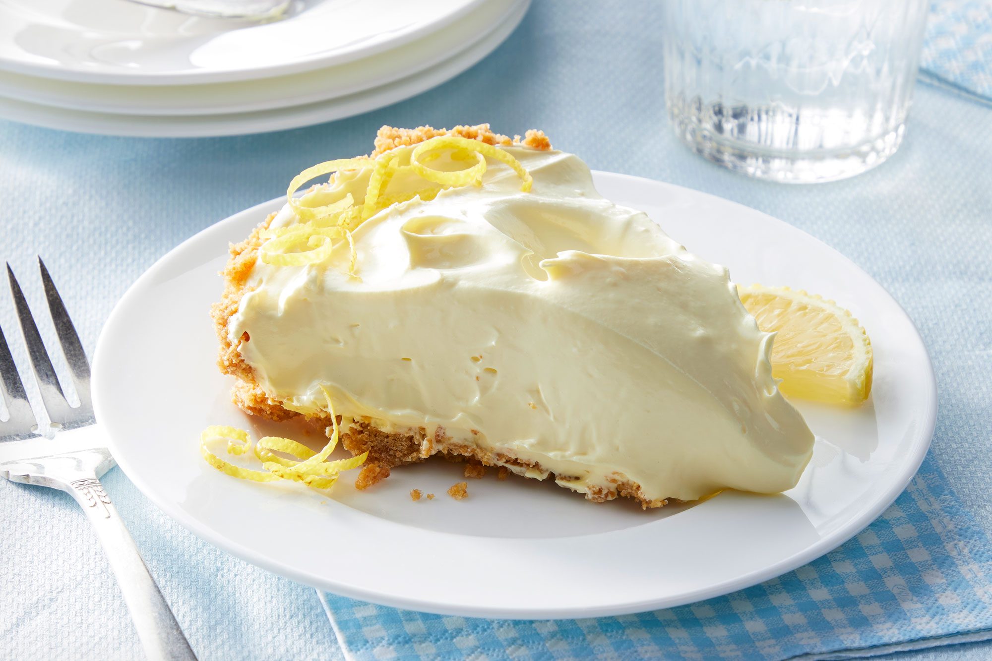 A slice of lemonade icebox pie served on a white ceramic plate with a fork placed next to it