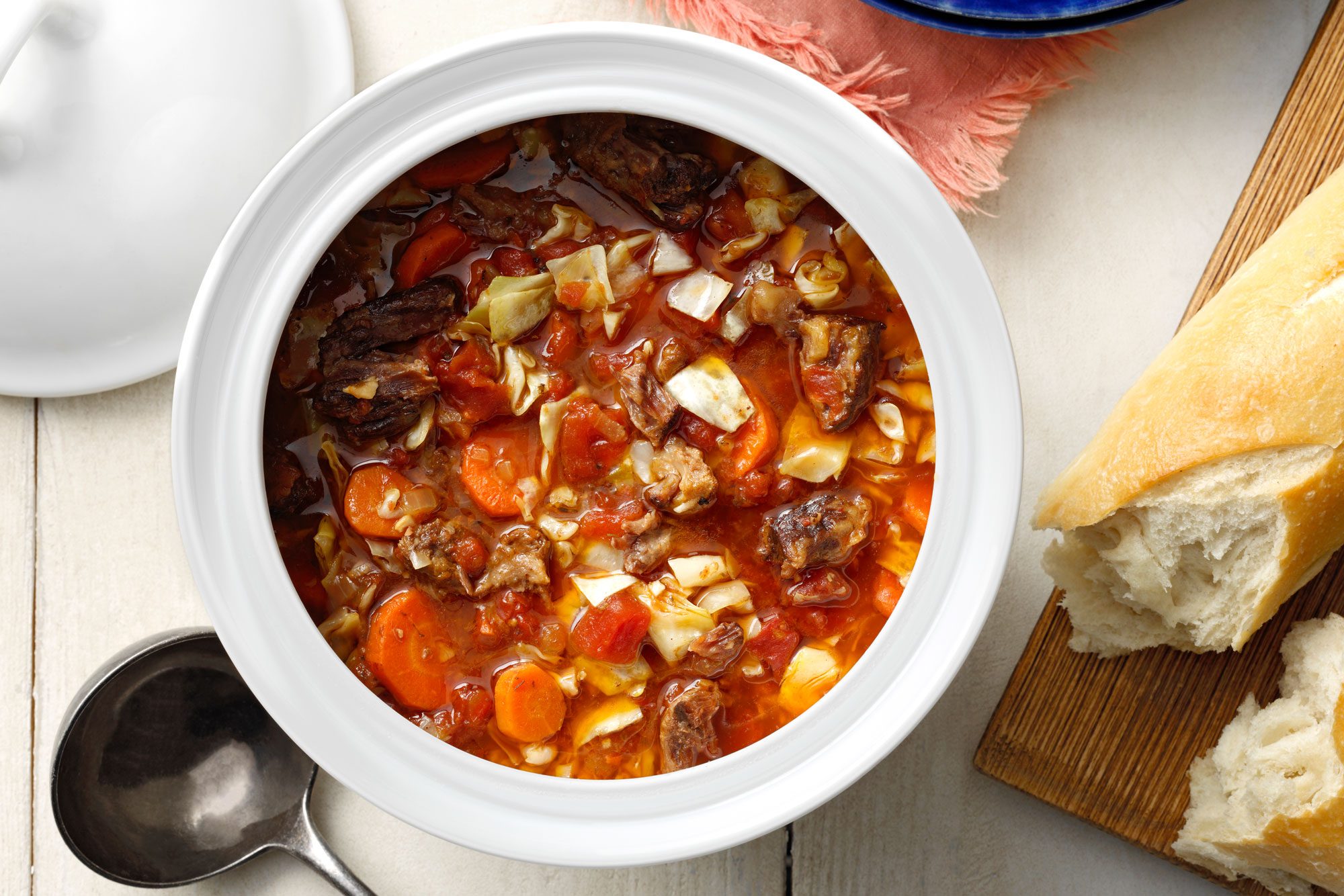 Oxtail Soup with serving spoon and bread loaf on cutting board