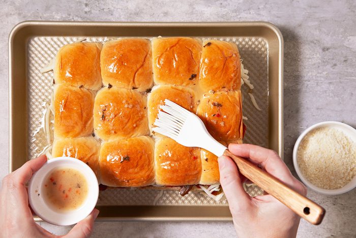 Brushing the top half of the pizza slider with butter mixture