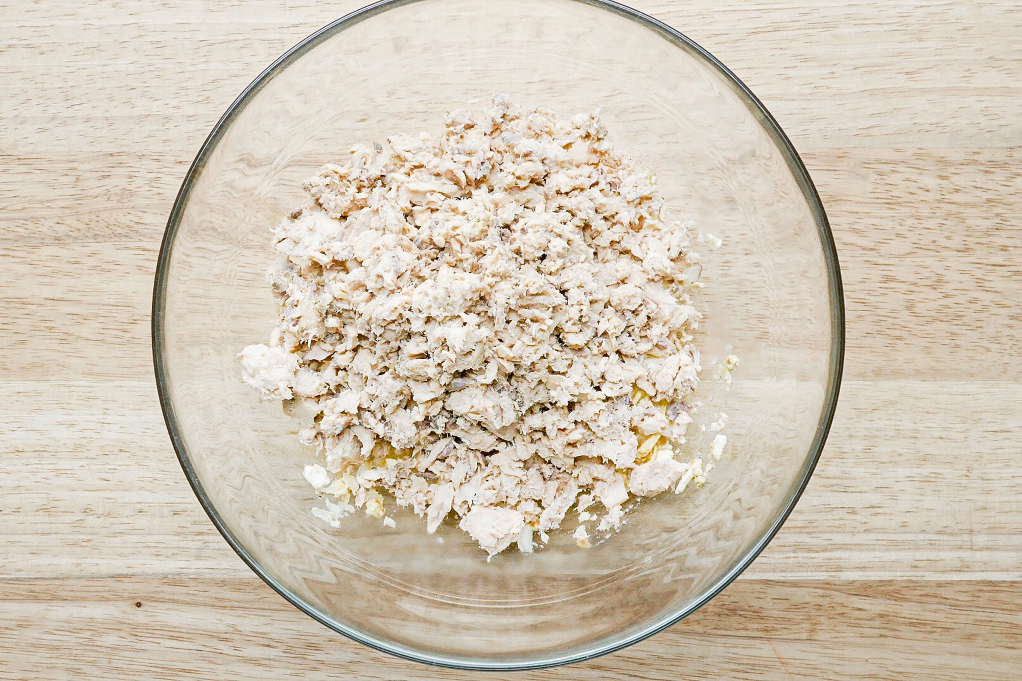 minced salmon in a glass bowl on a wooden surface