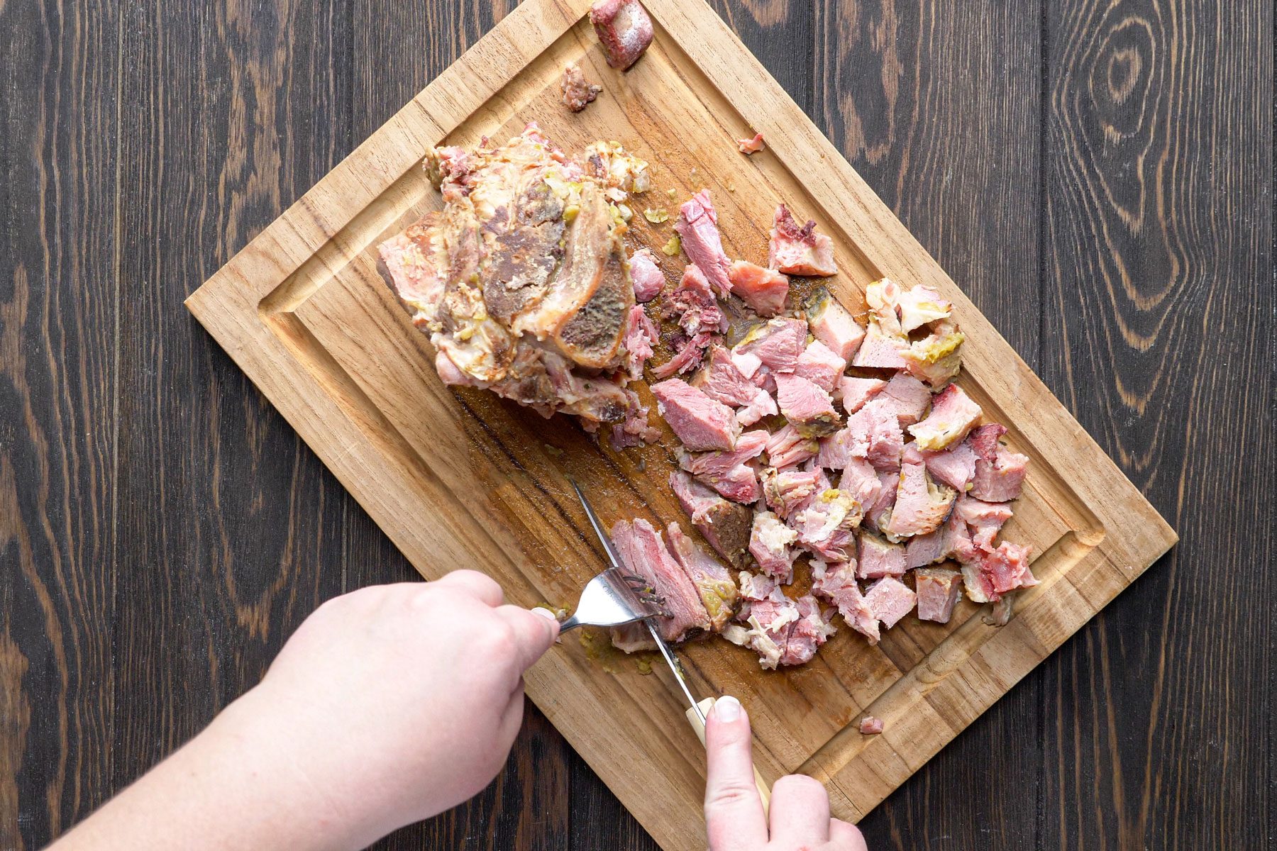 Cutting the meat into small dice on a wooden tray with knife