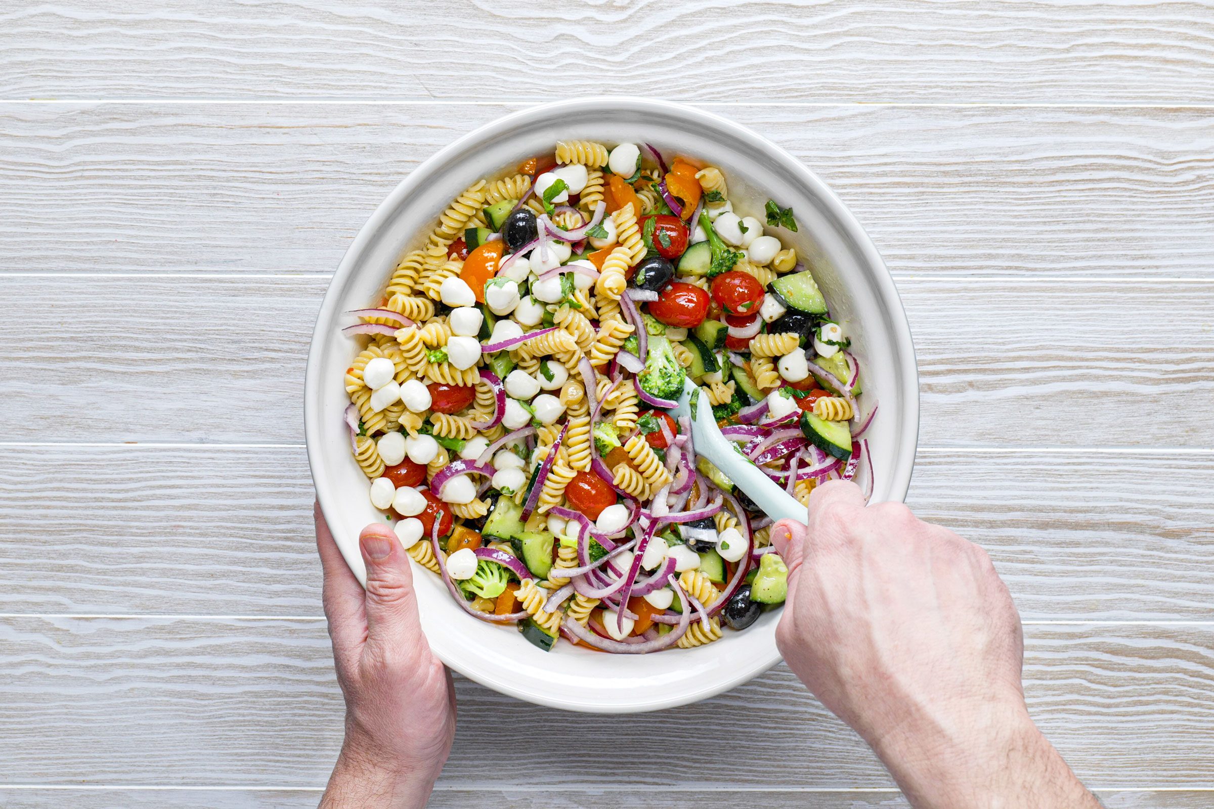 mixing pasta salad in a bowl