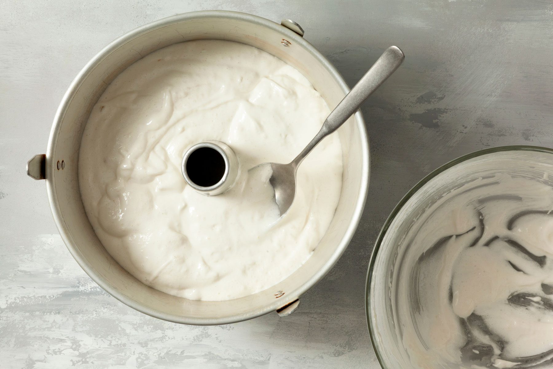 Cream mixture with a spoon in a tube pan on a kitchen countertop