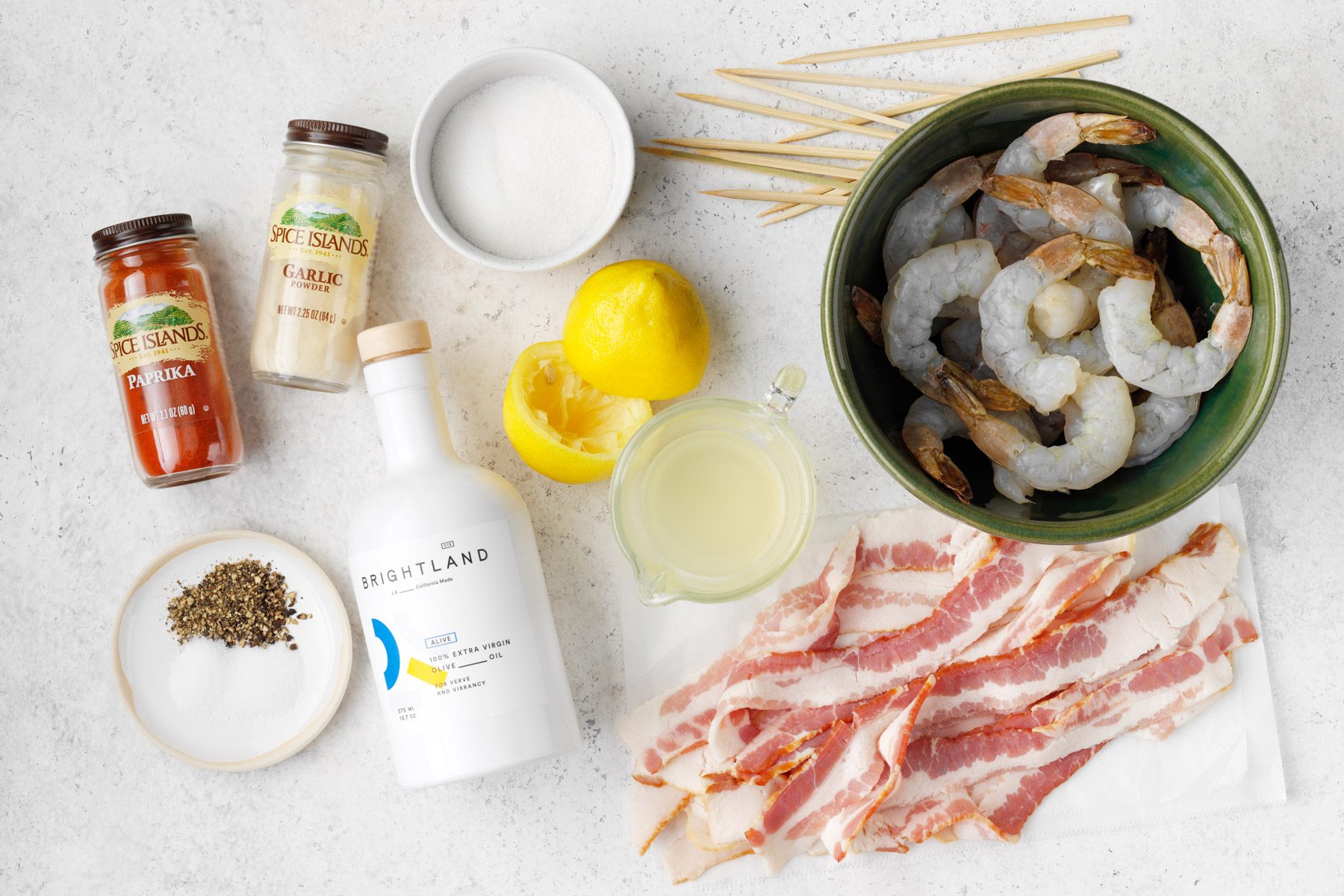 A bowl of shrimp and bacon with spices and lemons