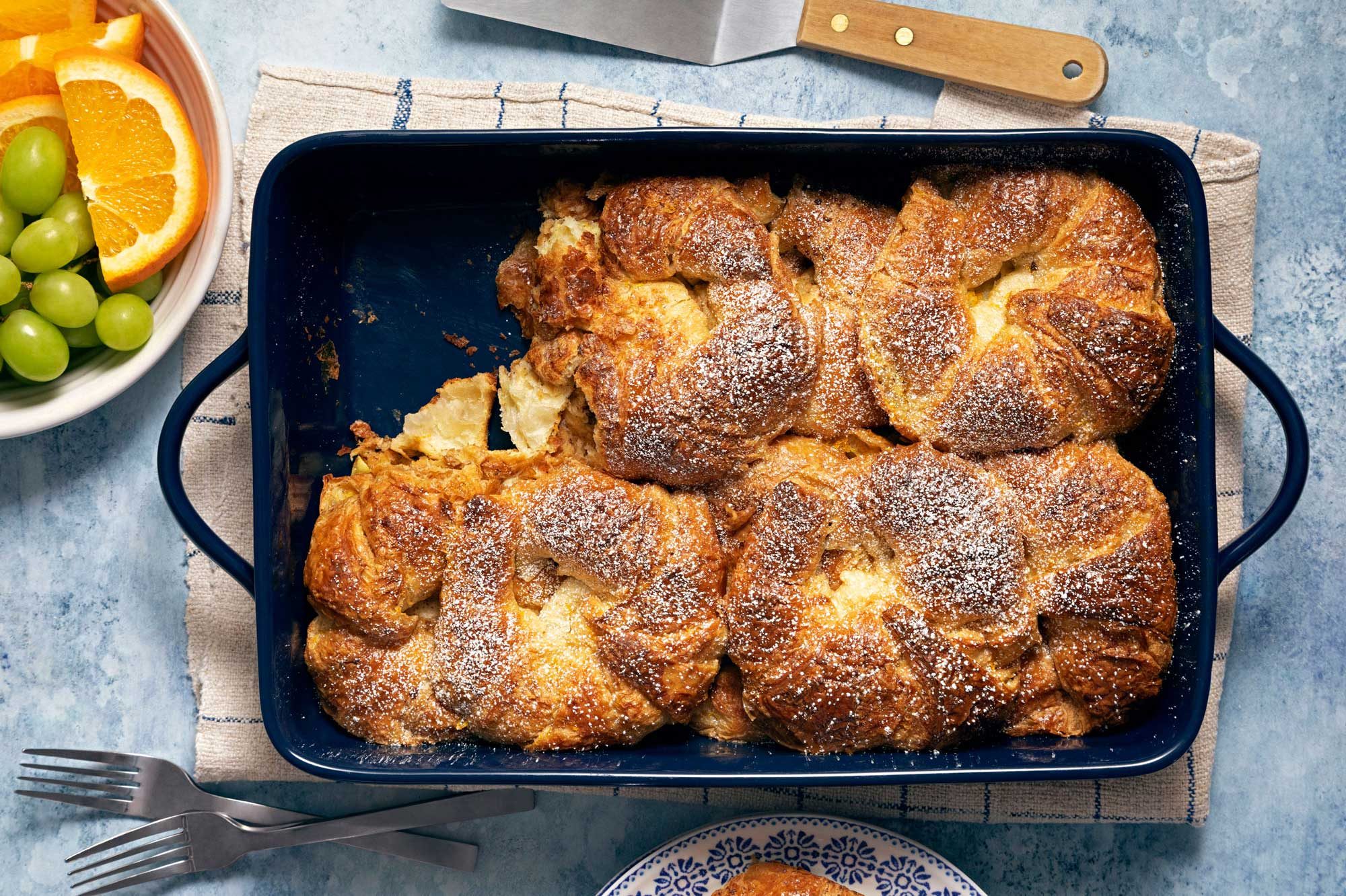 Croissant French Toast Bake in a serving pan with fruits on the side