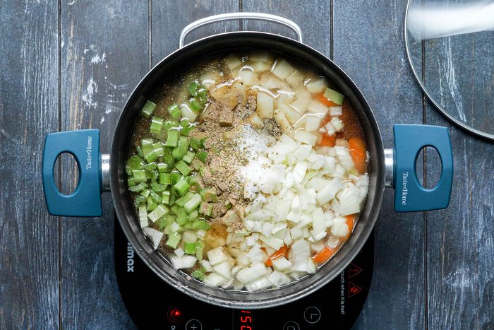 Mixing water, carrots, potatoes, onion, celery, beef bouillon granules in a large saucepan