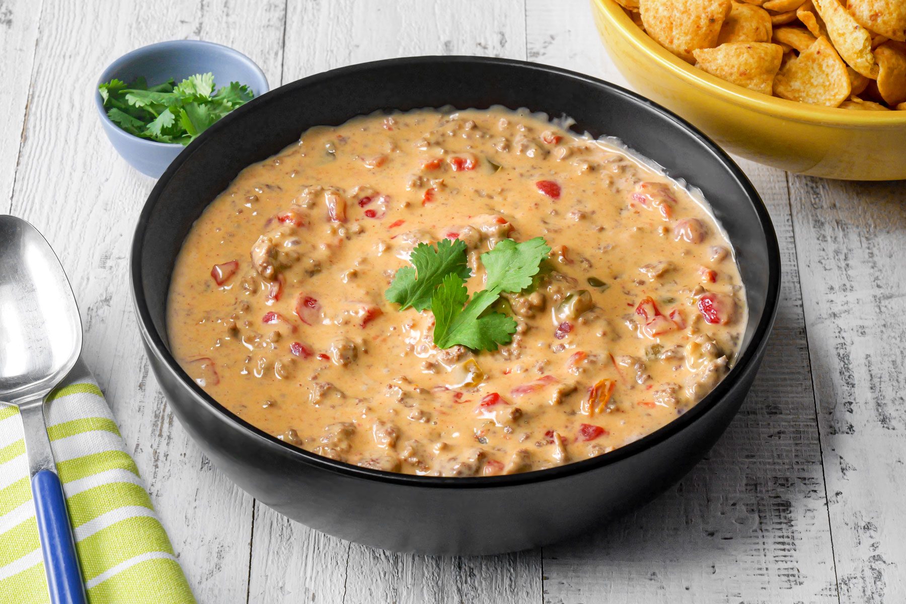 Rotel Dip in a large bowl with a spoon on a wooden surface 