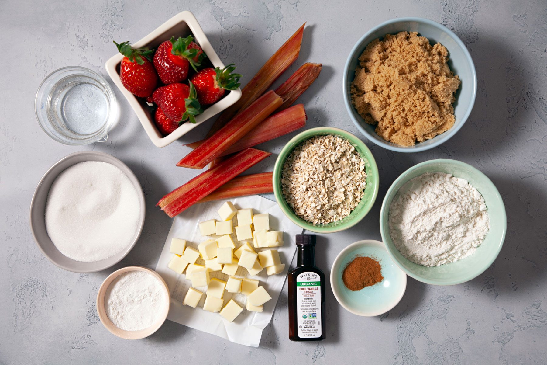 Flour oats butter strawberries arranged on a marble countertop