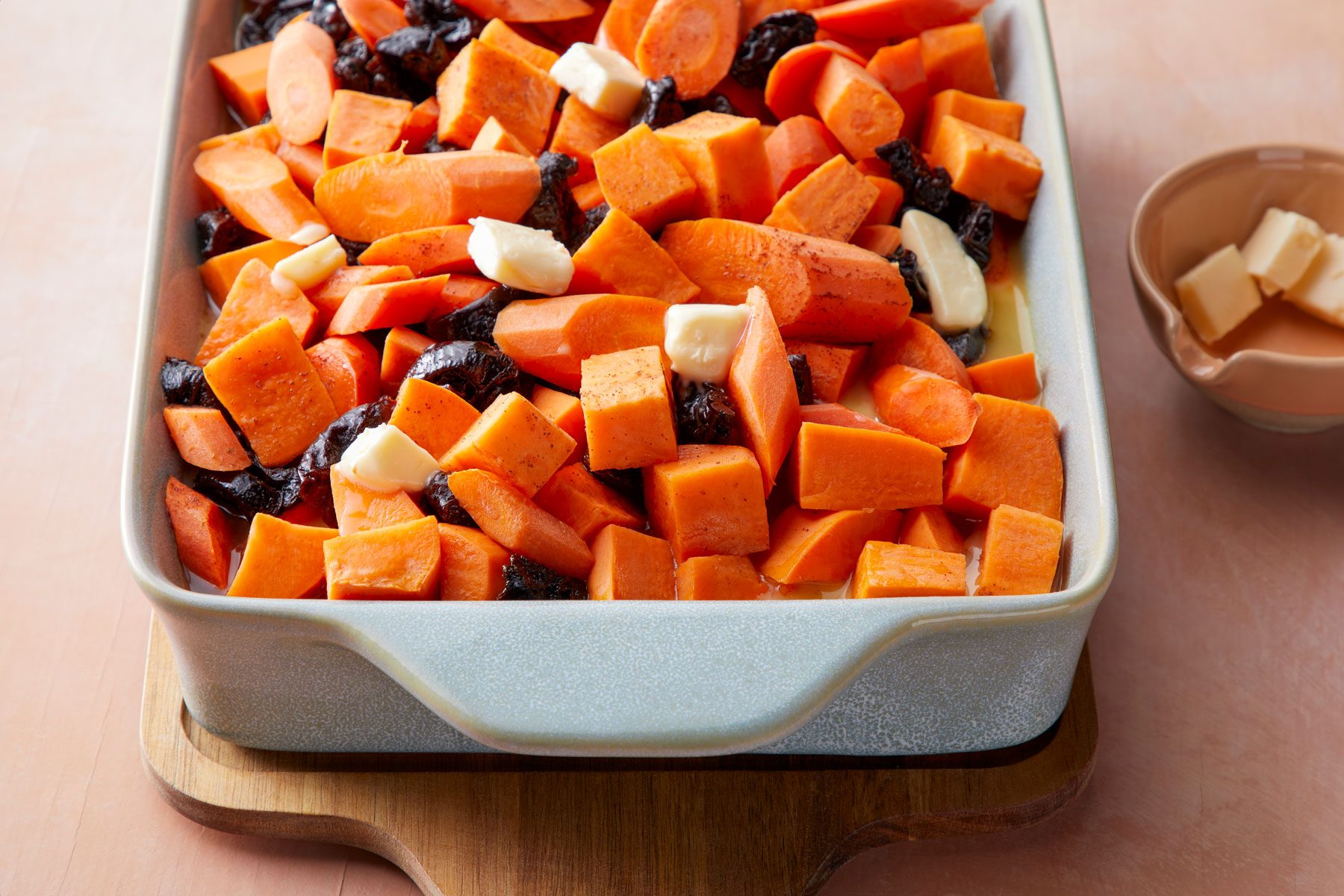 Slices of butter on vegetables in a large baking pan