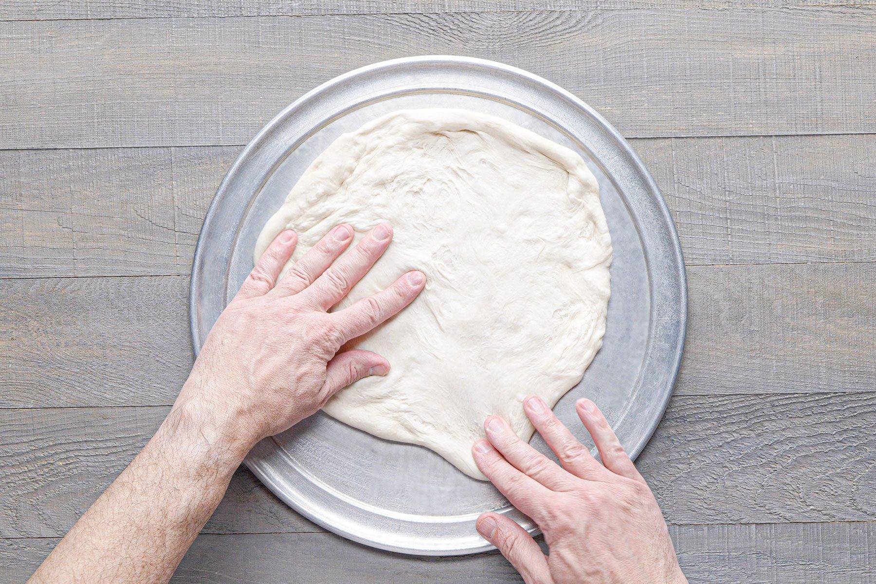 Pressing the dough on greased pan