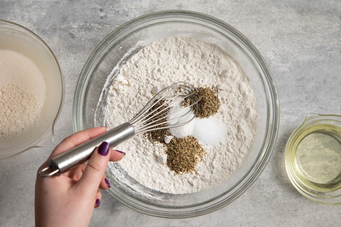 A hand whisking a mixture of flour and spices