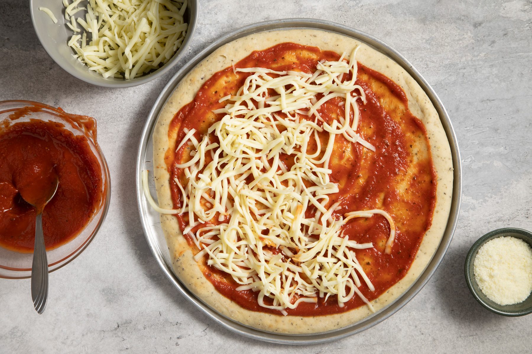 A pizza in pizza pan with cheese on it