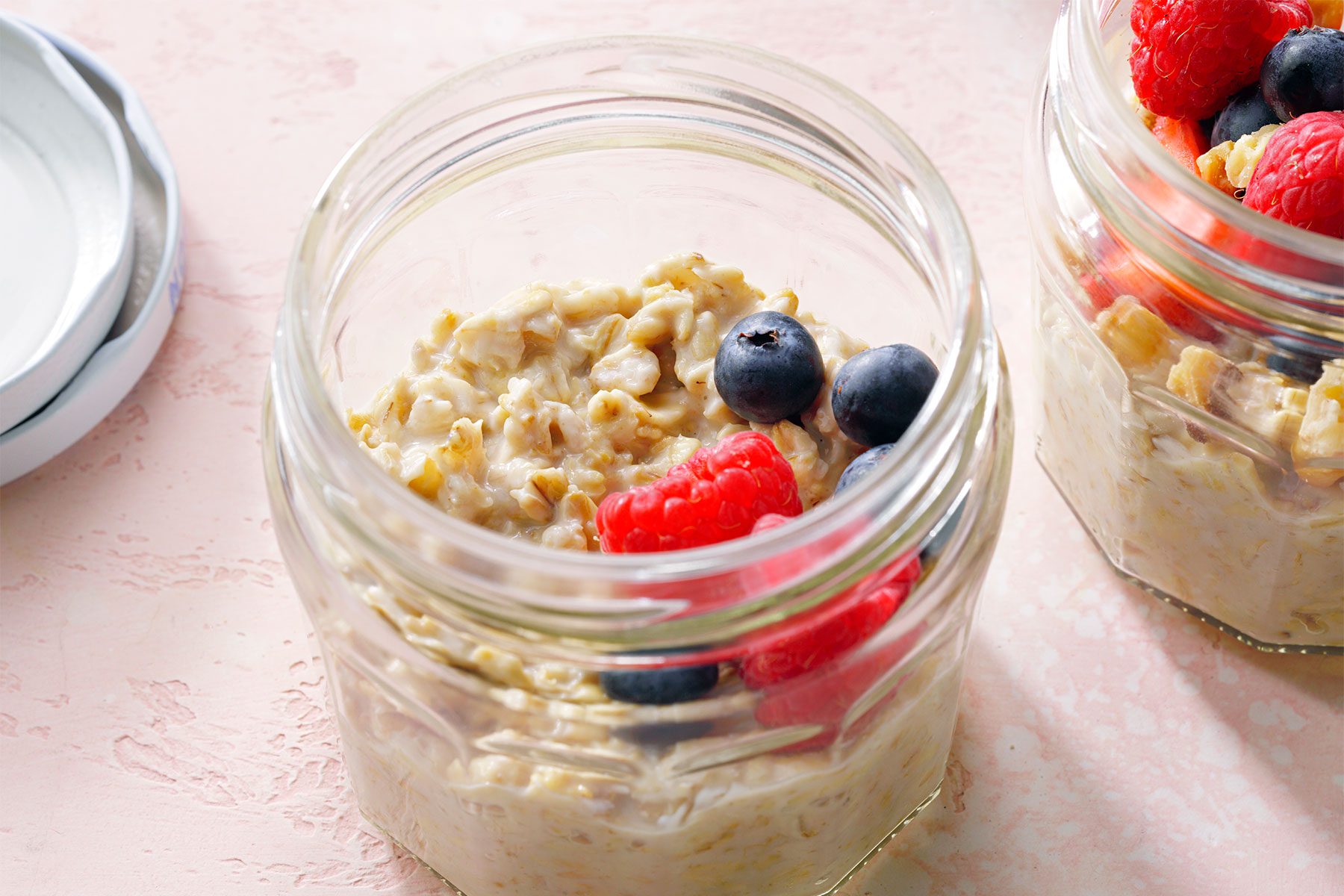 high angle shot of overnight oatmeal topped with fruits and nuts in a mason jar