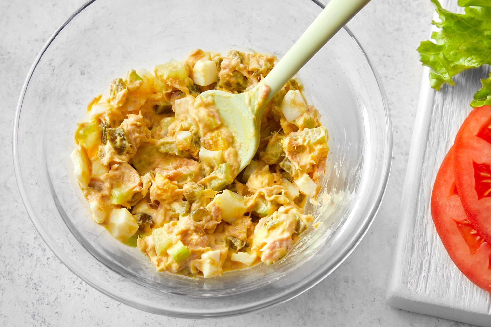 Overhead shot of Tuna Salad With Egg in a large mixing bowl; marble background;