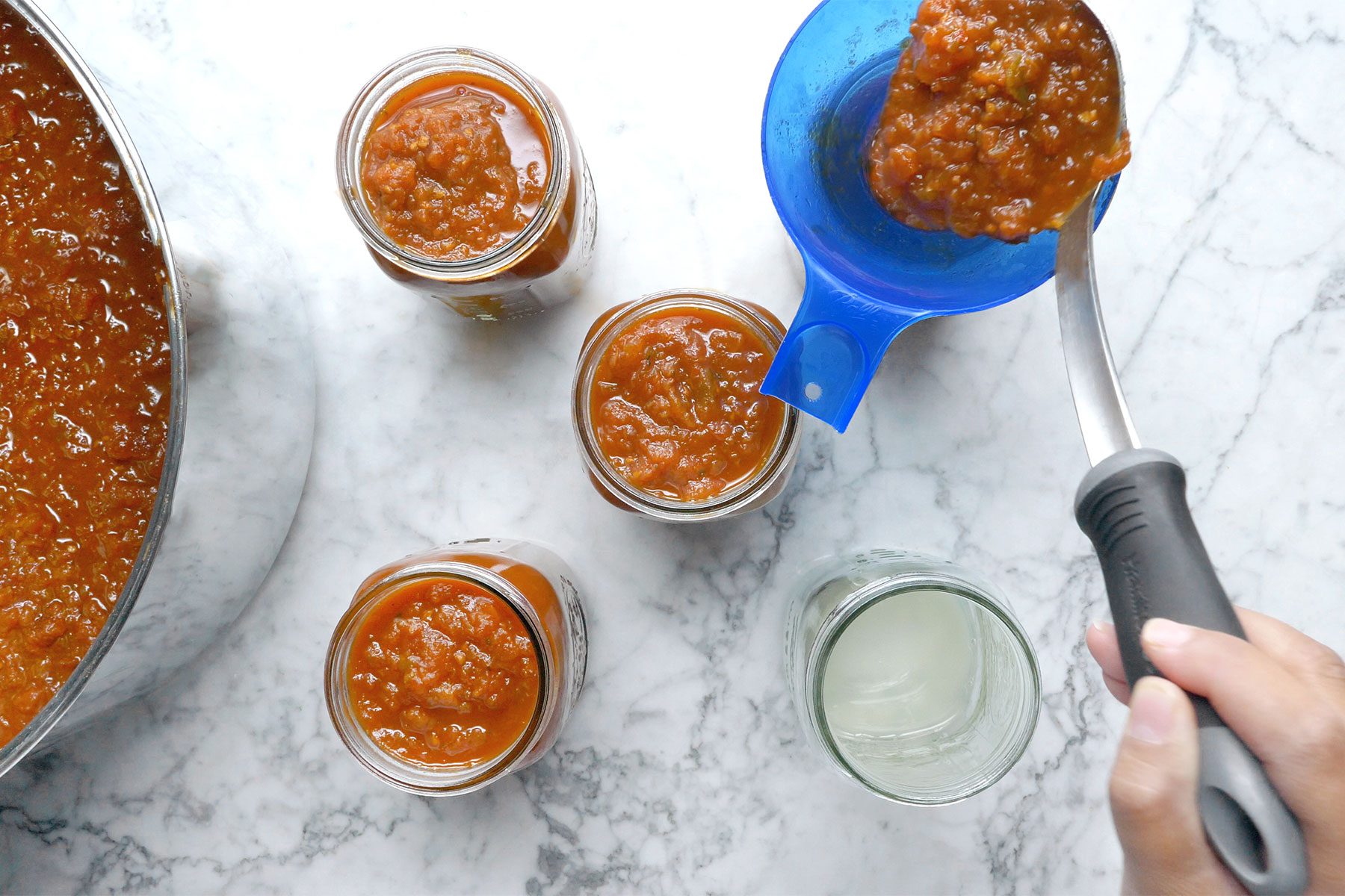 Overhead shot of filling the bottle jars; serving spoon; marble background;