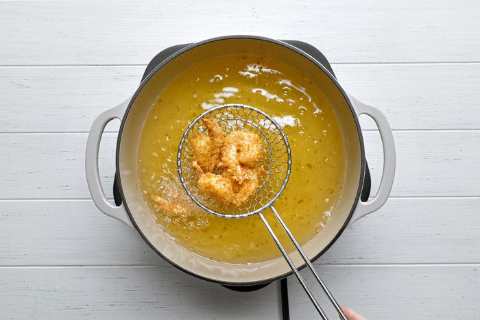 Overhead shot of fry shrimp in batches until golden brown; 3-4 minutes; white wooden background;