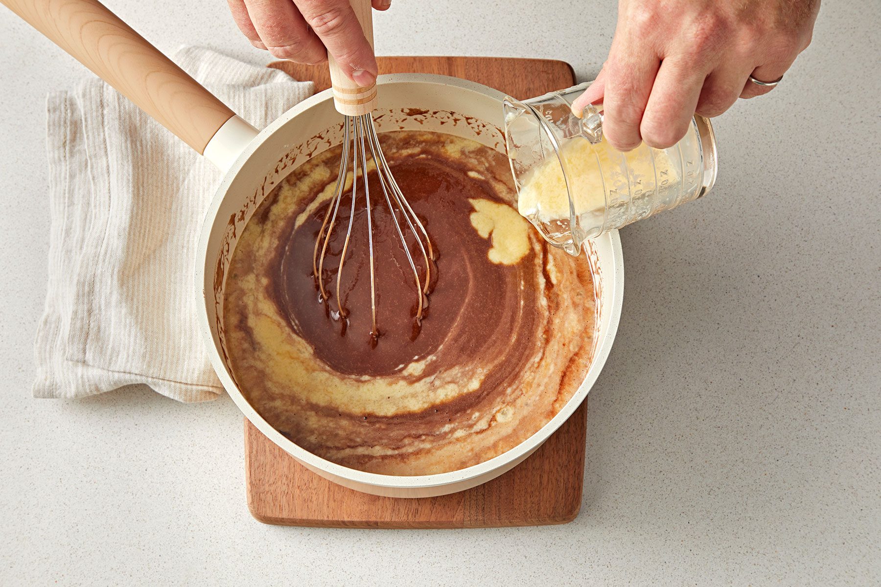 overhead shot of eggs adding in the cocoa batter in a saucepan