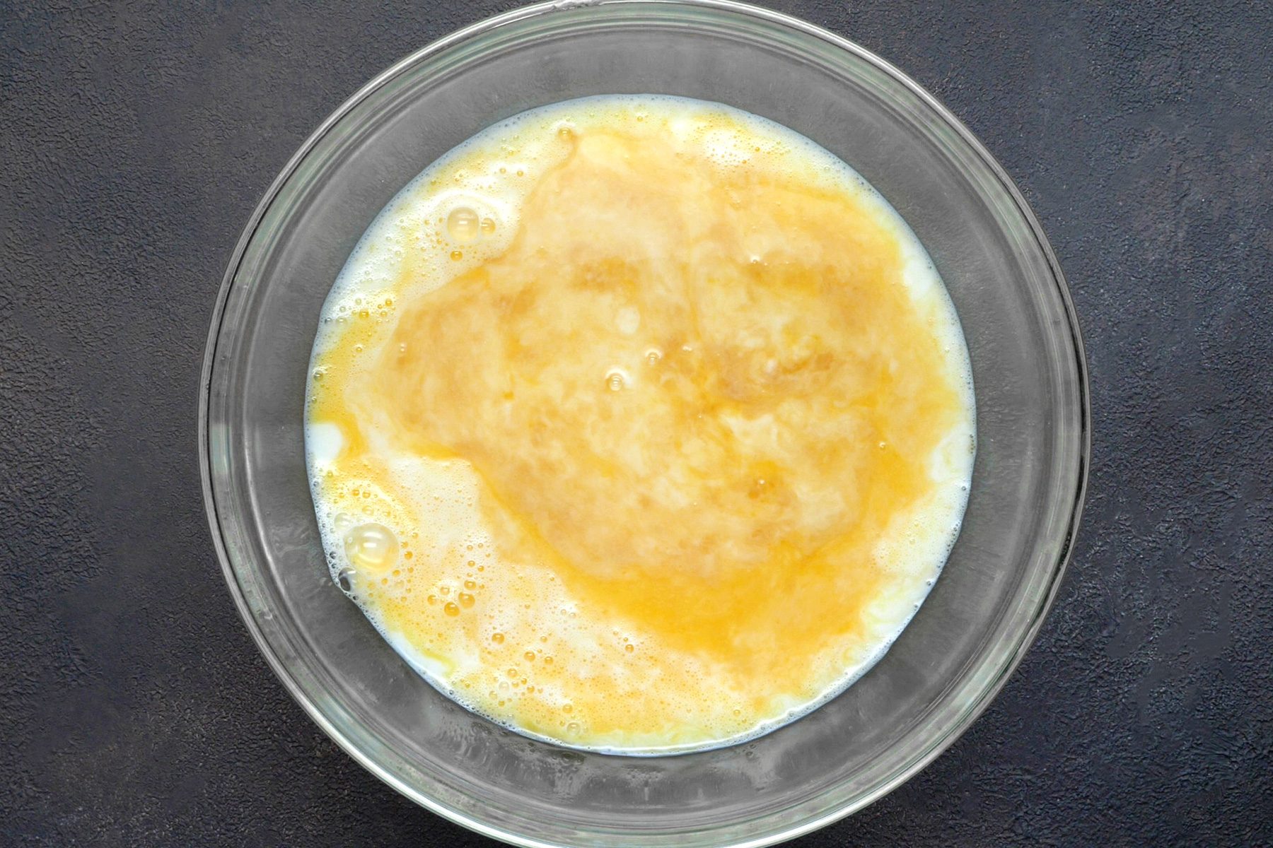 A bowl filled with a mixture of eggs, milk, sugar, vanilla, and salt.