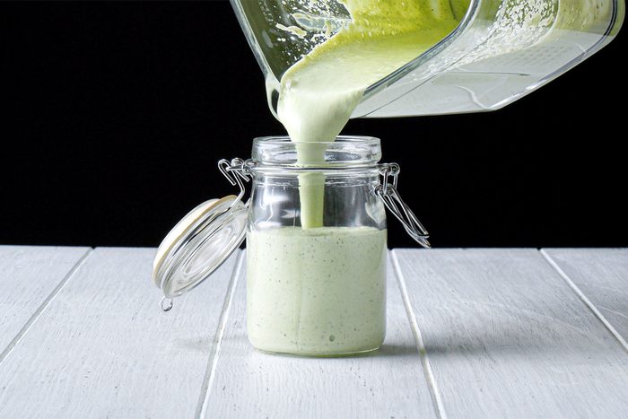 Table view shot of transfering the smooth mixture into a glass jar; white wooden background;
