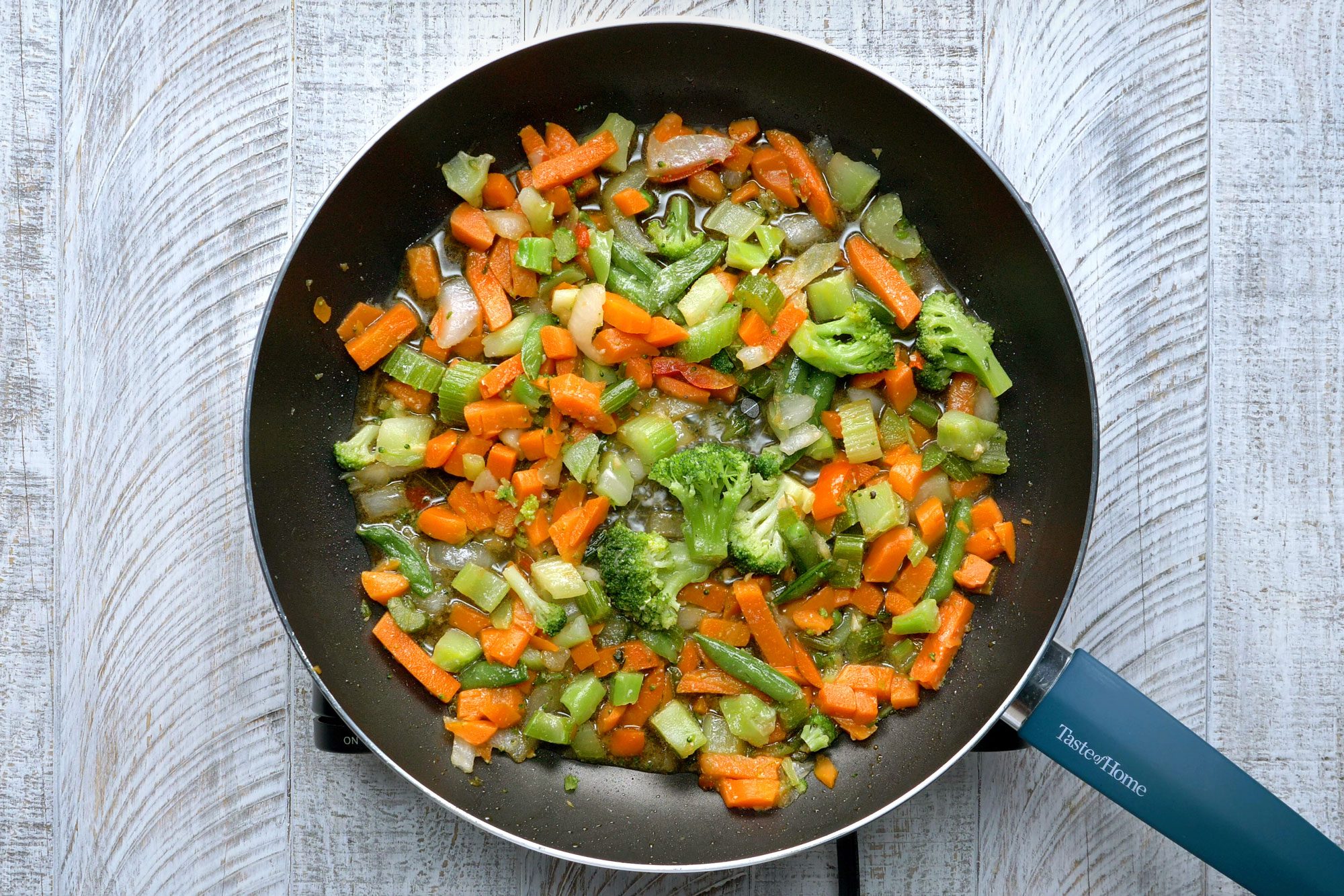 Overhead shot of a same large skillet; stir- fry vegetables blend in remaining oil; just until tender; wooden background;