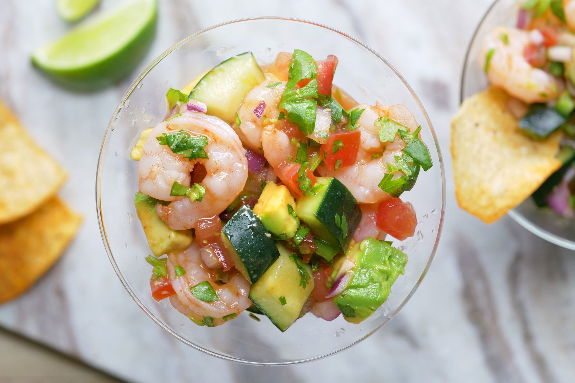 A glass of Easy Mexican Shrimp Cocktail with chips and a lime wedge