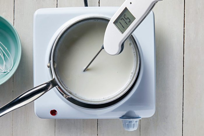 overhead shot; white background; In a small saucepan, heating the milk and checking the temperature with digital thremometer;