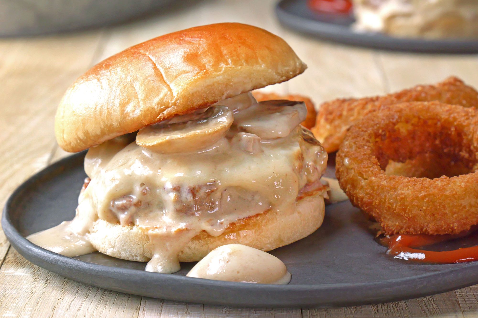 Mushroom and Swiss Burger with mushrooms and onion rings on a plate