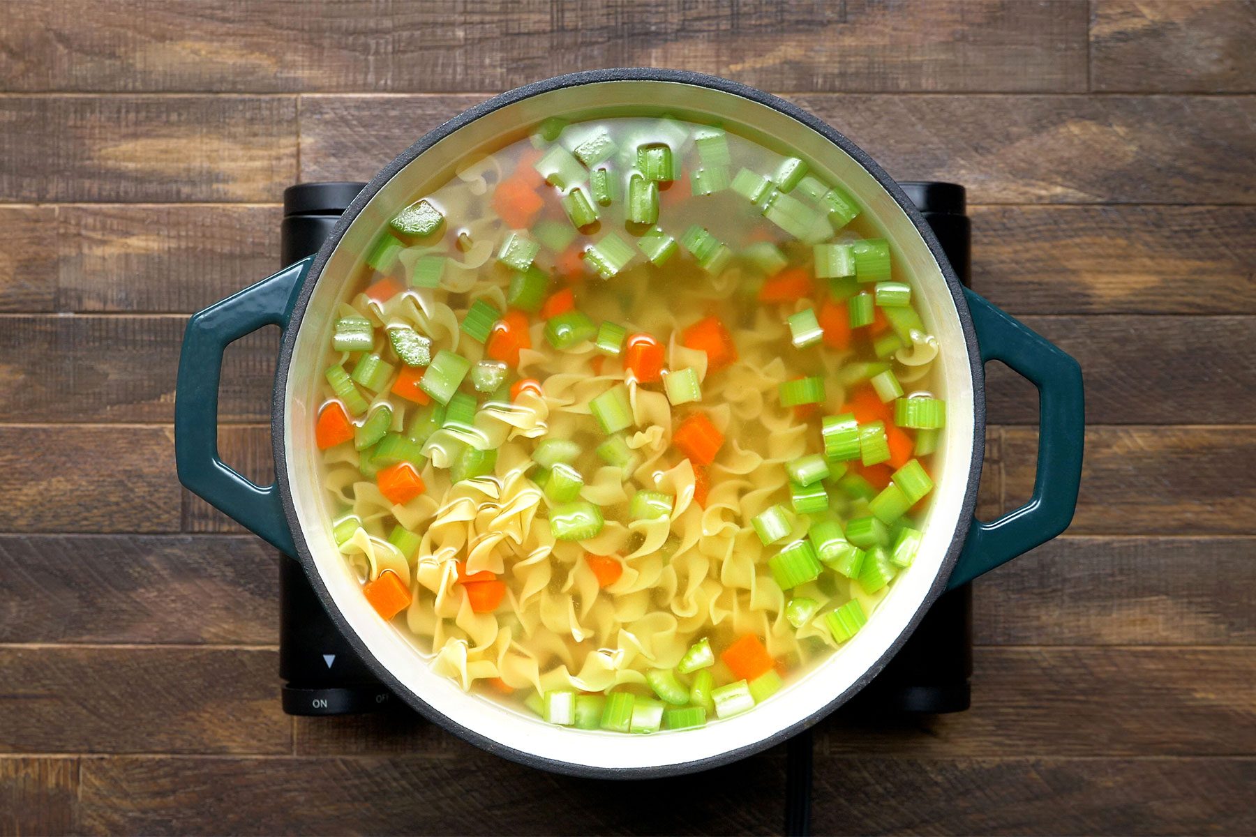 overhead shot of carrots and noodles in a dutch oven