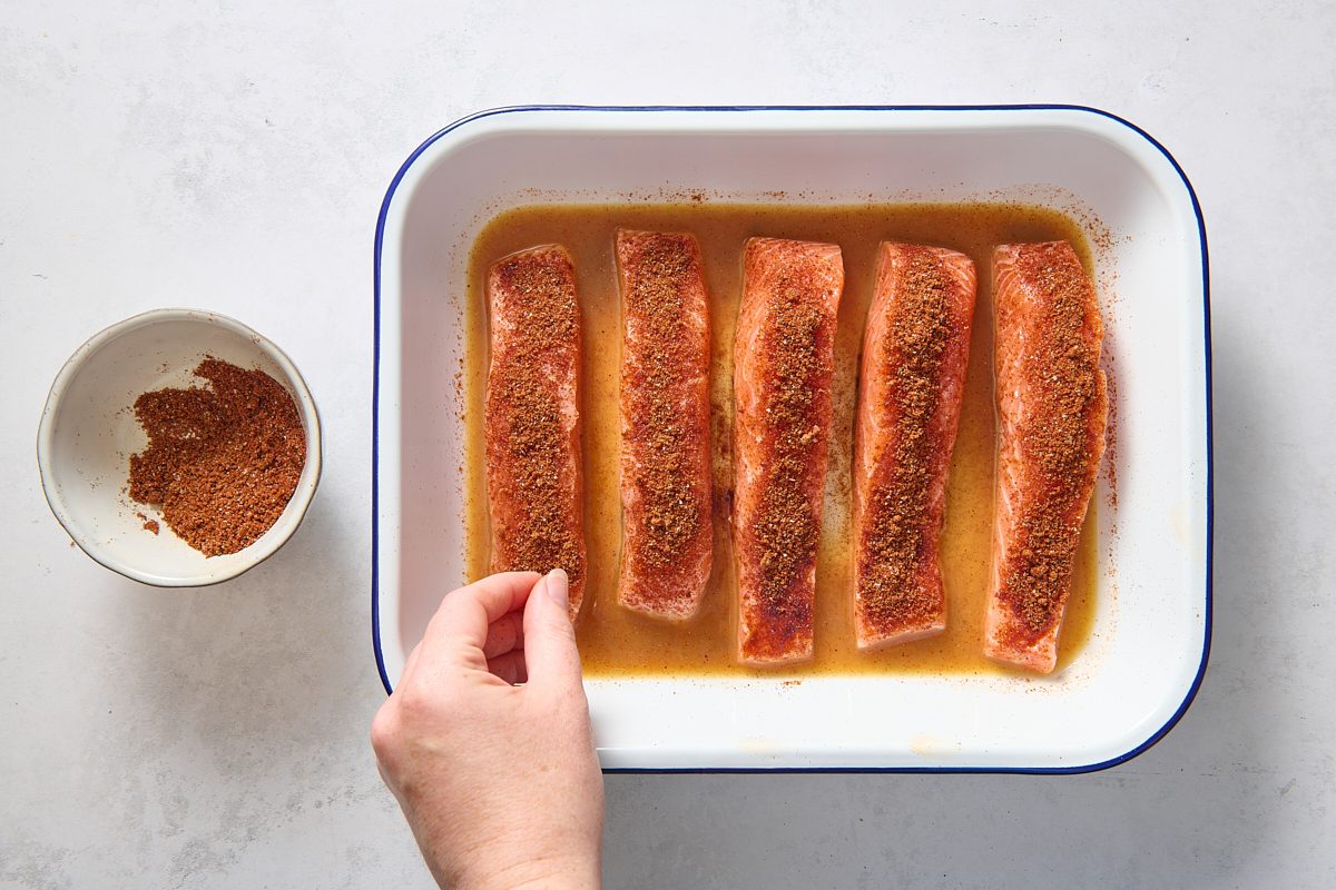 Sprinkling barbecue seasoning over the salmon fillets