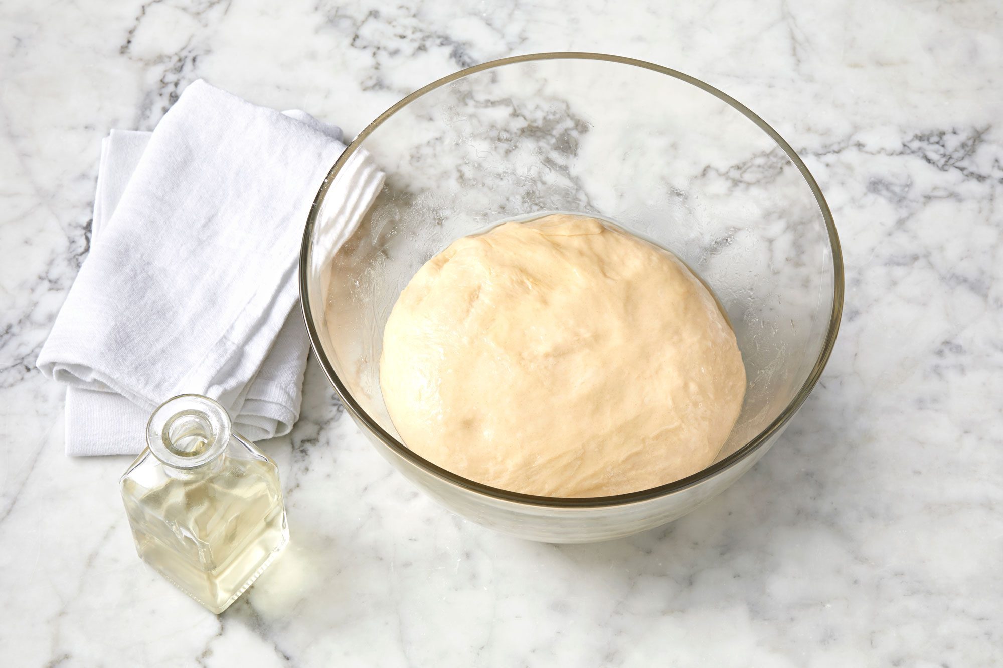 wide shot of dough in a glass bowl; marble surface;