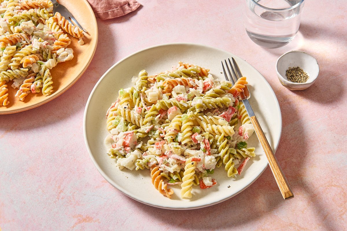 Angled shot of crab pasta salad on a plate with a fork