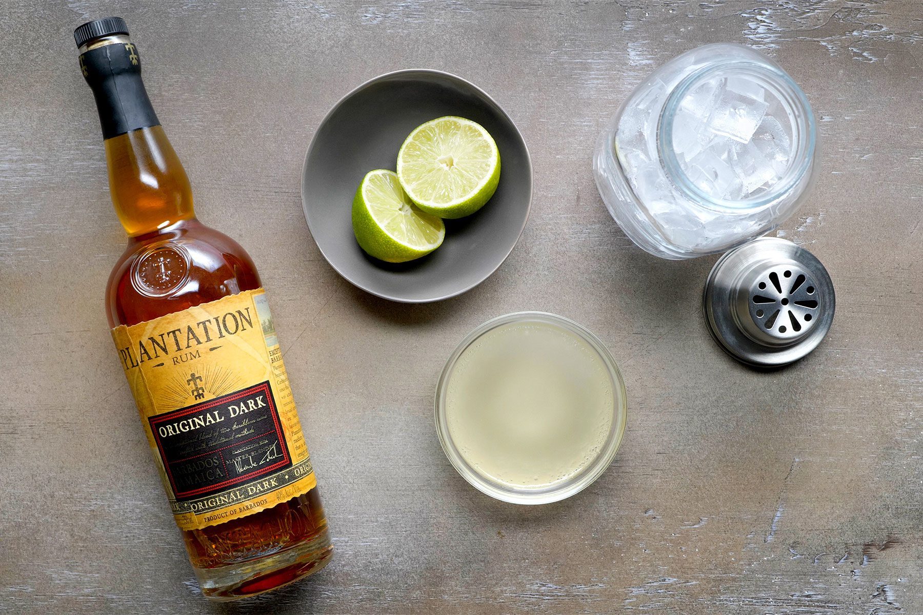 overhead shot; wooden textured background; dark rum bottle with other ingrediants with shaker