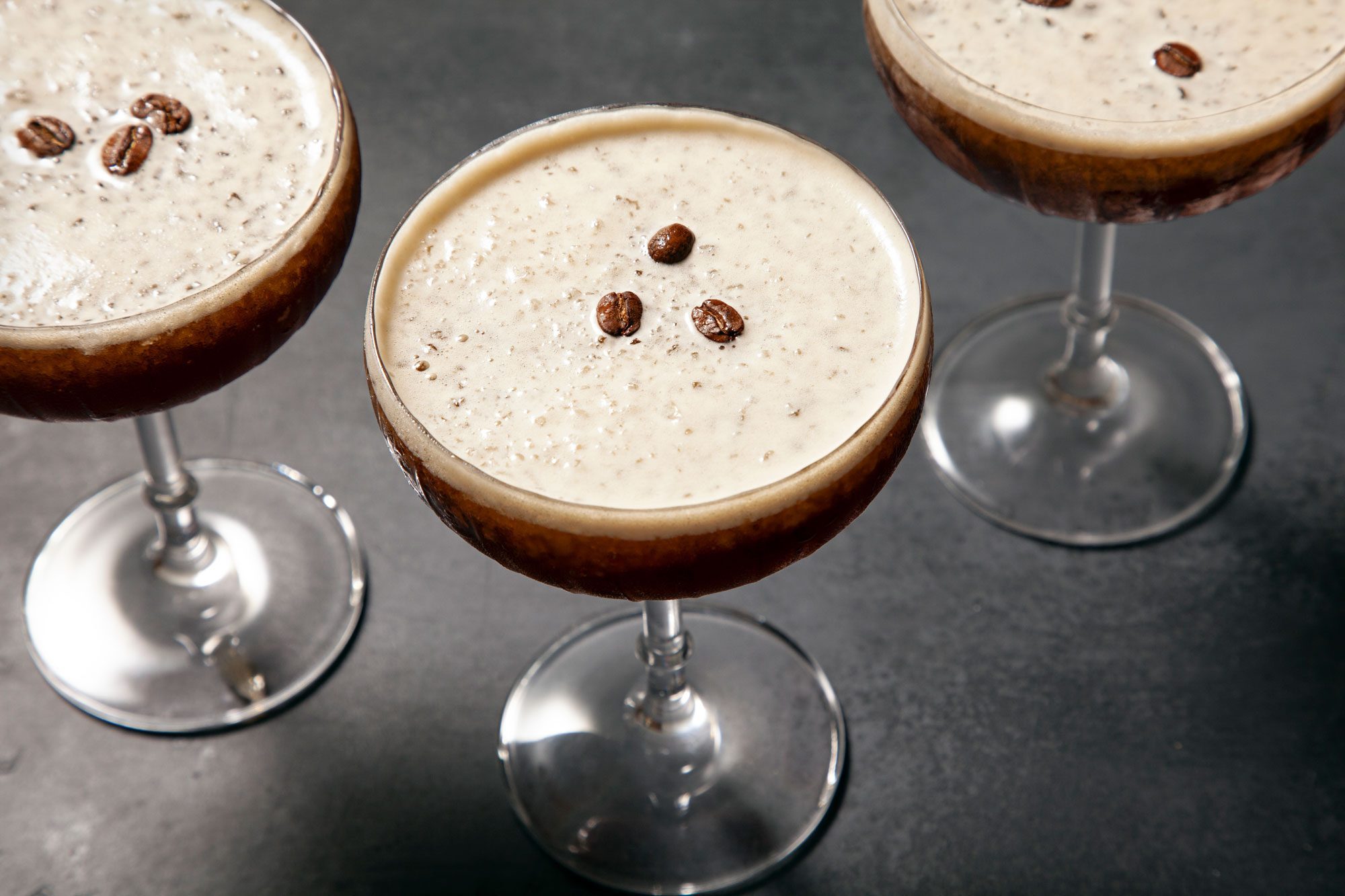 High angle view shot of Frozen Espresso Martini; in martini glasses; garnish with coffee beans; coffee beans bowl; dark grey background;