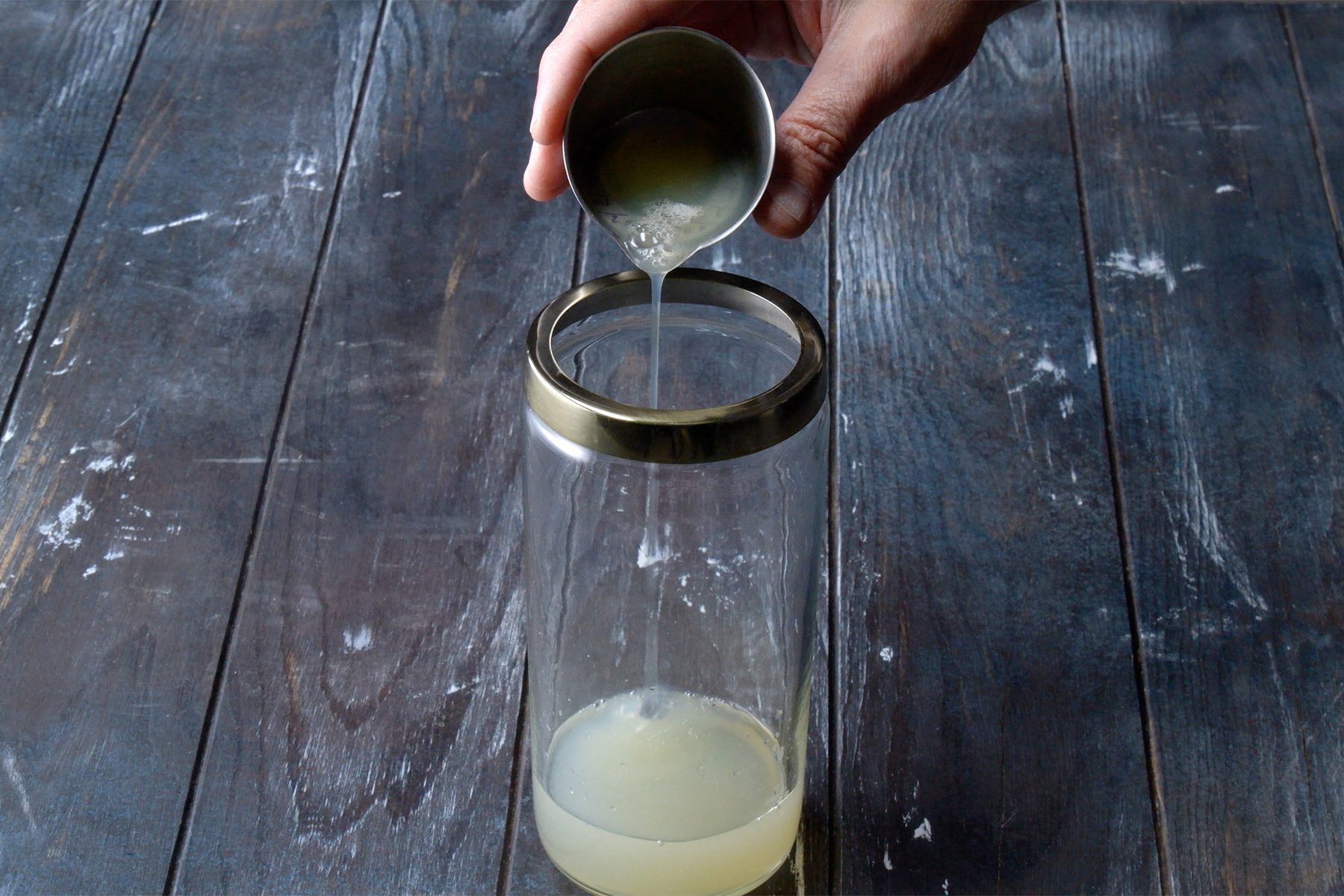 overhead shot; wooden background; pouring ingrediants into shaker