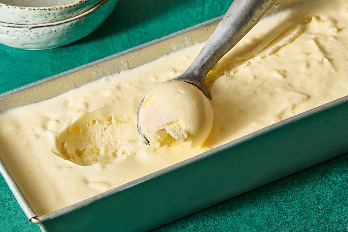 Pineapple ice cream being scooped out of a container