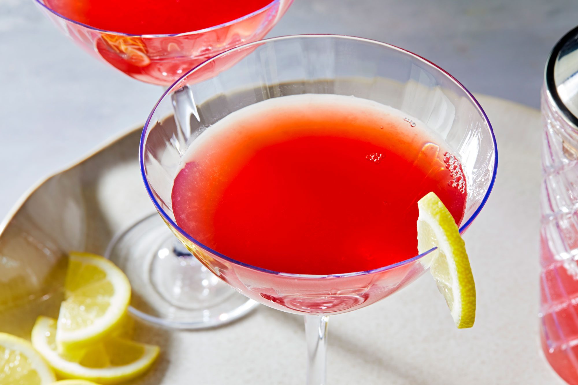 Refreshing Pomegranate Martini, served in two glasses, adorned with lime slices